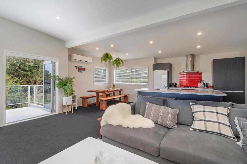a living room with a couch and a kitchen at Wharf Landing - Harbour View with Sunny Balcony, Walk to Town in Coromandel Town
