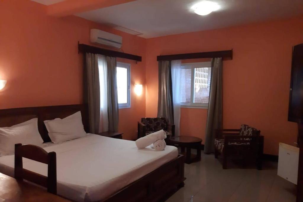 a bedroom with a bed and a table and two windows at Hôtel Concorde in Antsiranana