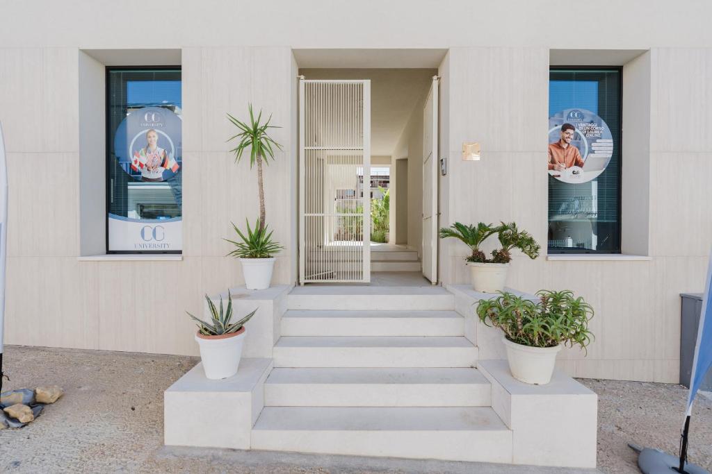 a white building with potted plants on the steps at Gc Luxury Apartments e Spa in Santa Margherita di Belice