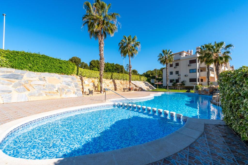 a swimming pool with palm trees and a building at Sunnygolfbeach in Orihuela Costa