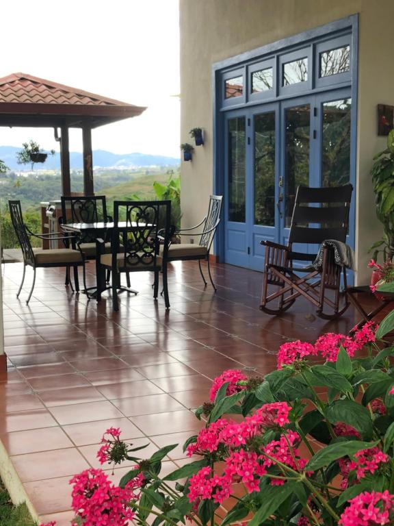 a patio with a table and chairs and pink flowers at Casa Bartzis, every stay comes with a free professional massage in Orosí