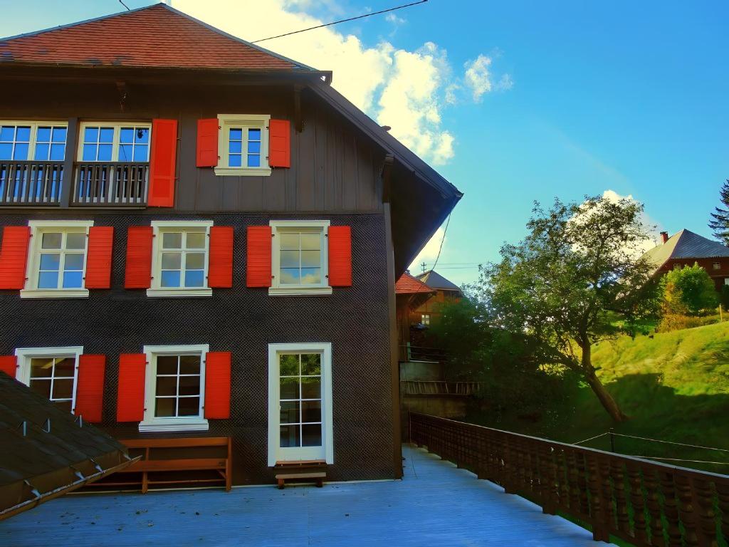 a house with red and white windows and a fence at Schwarzwaldbauernhaus Bernau in Bernau im Schwarzwald