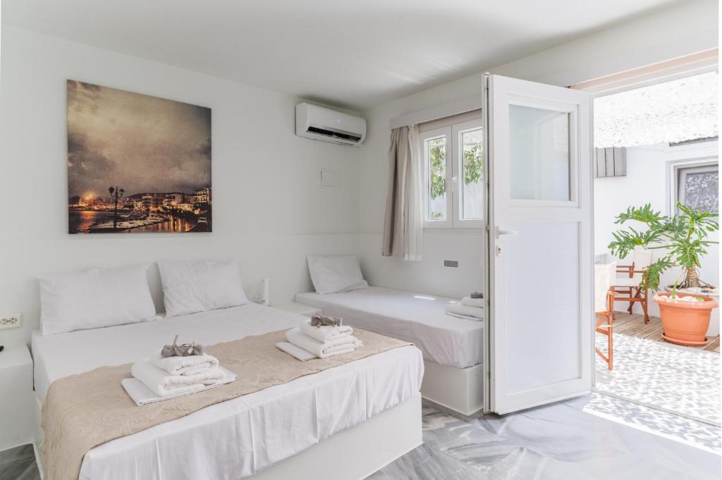a white room with two beds and a window at A Tinian Room 5 in Tinos
