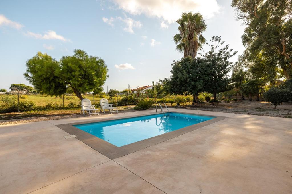 a swimming pool in a yard with two chairs and trees at Estudio La Cochera in Deltebre