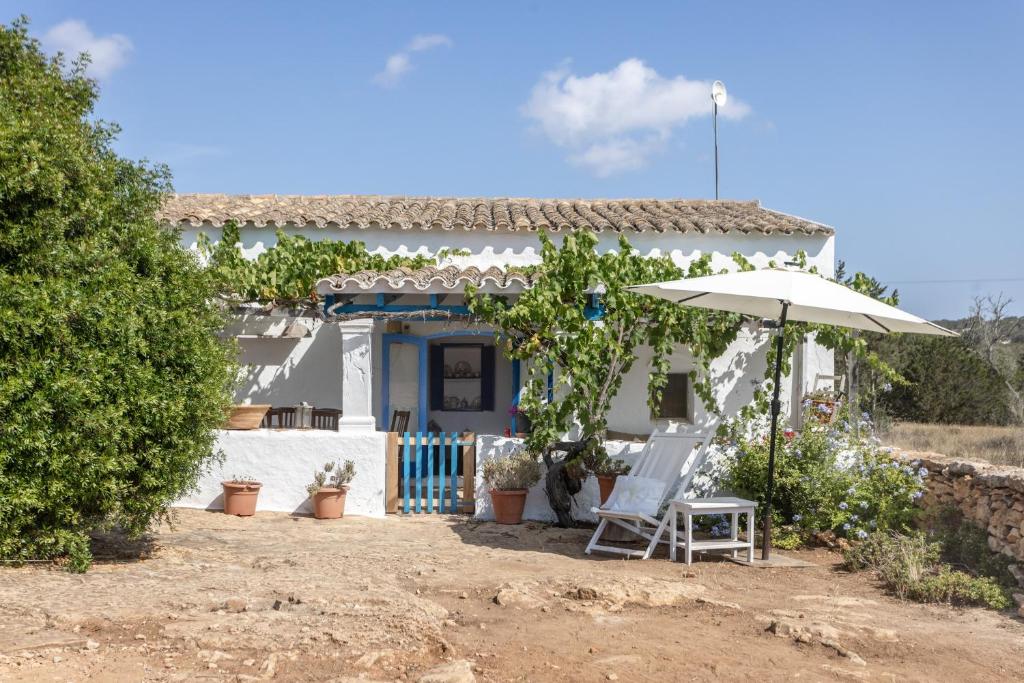 a white house with two chairs and an umbrella at Can Vicent in Illes Balears