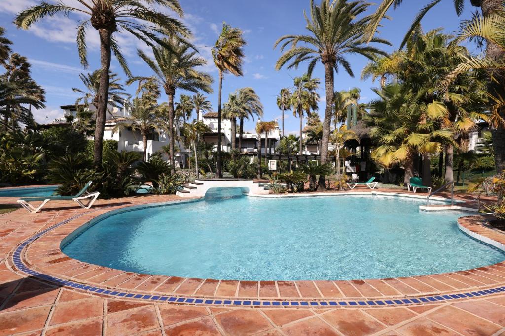 a swimming pool with palm trees in a resort at Frontline paradise townhouse in Estepona