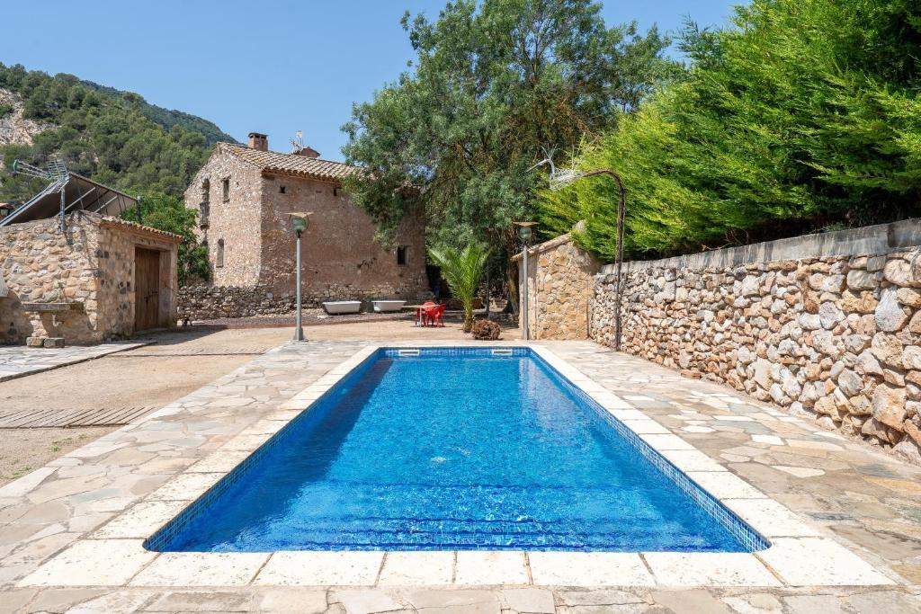 a swimming pool in a yard next to a stone wall at Serra de Prades in Montblanc