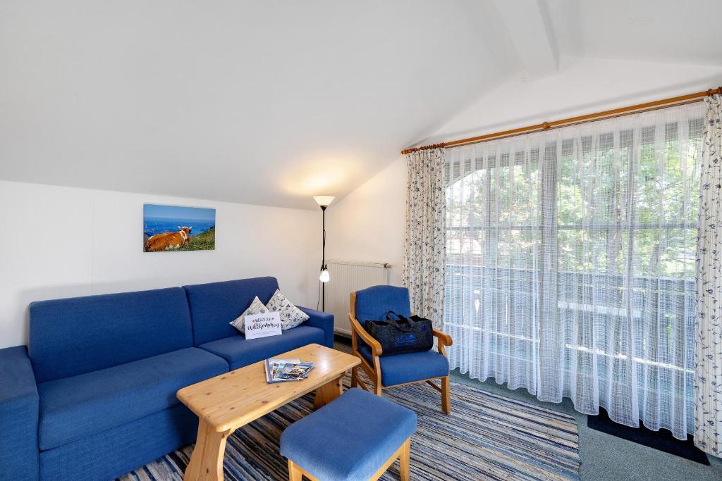 a living room with a blue couch and a table and a window at Fewo Brünnstein - Nr 60 Pool, Sauna in Oberaudorf