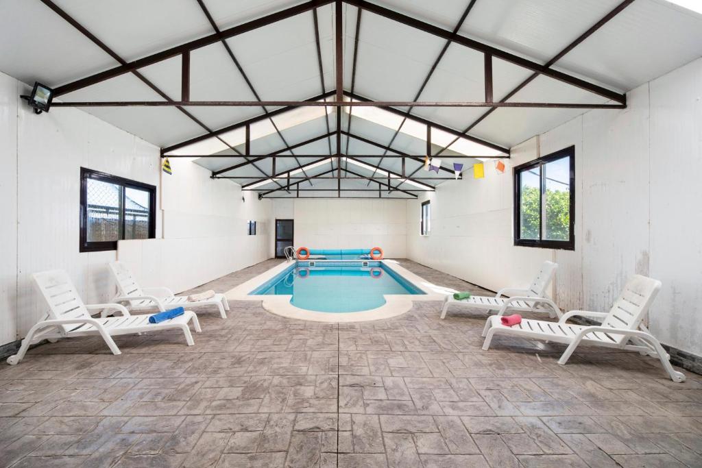 a pool room with chairs and a swimming pool at Villa Pastrana in Chipiona