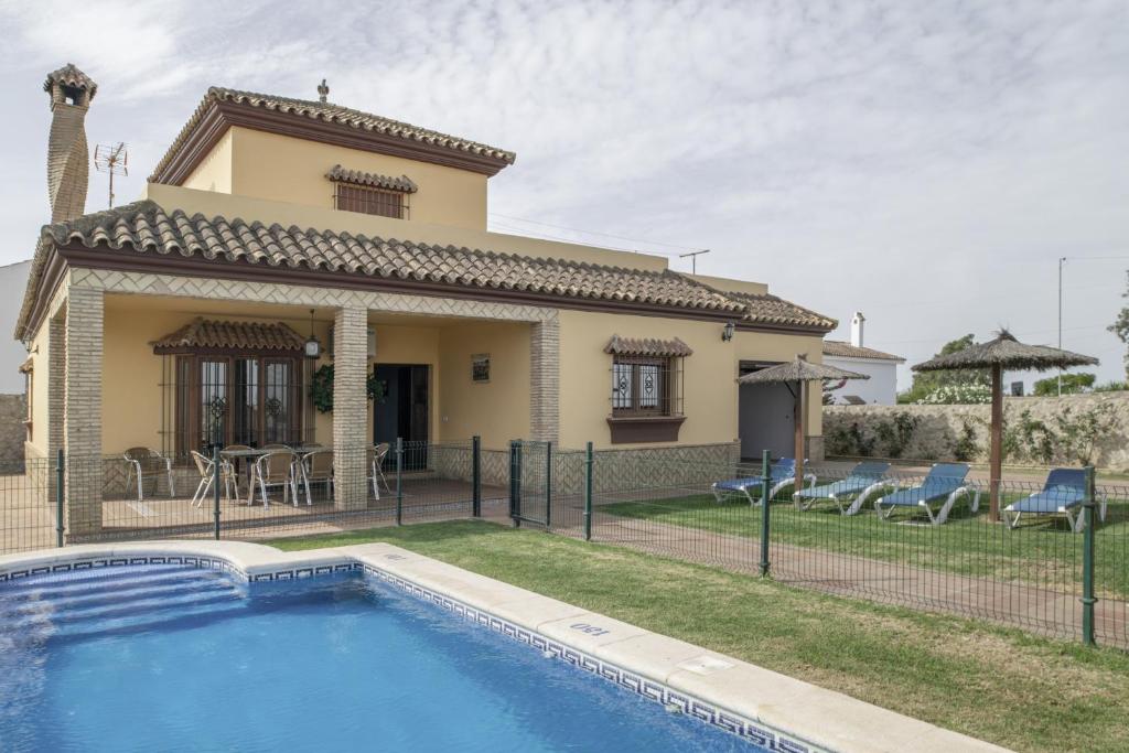 a villa with a swimming pool in front of a house at Casa Carmelo 1 familas o parejas in Conil de la Frontera