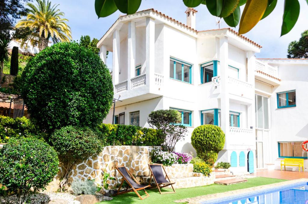 a large white house with chairs in front of it at El Riu del Cel in Lloret de Mar