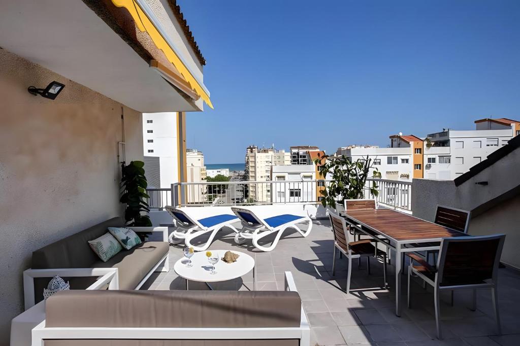 a balcony with a couch and tables and chairs at Atico Playa Gandia in Playa de Gandia