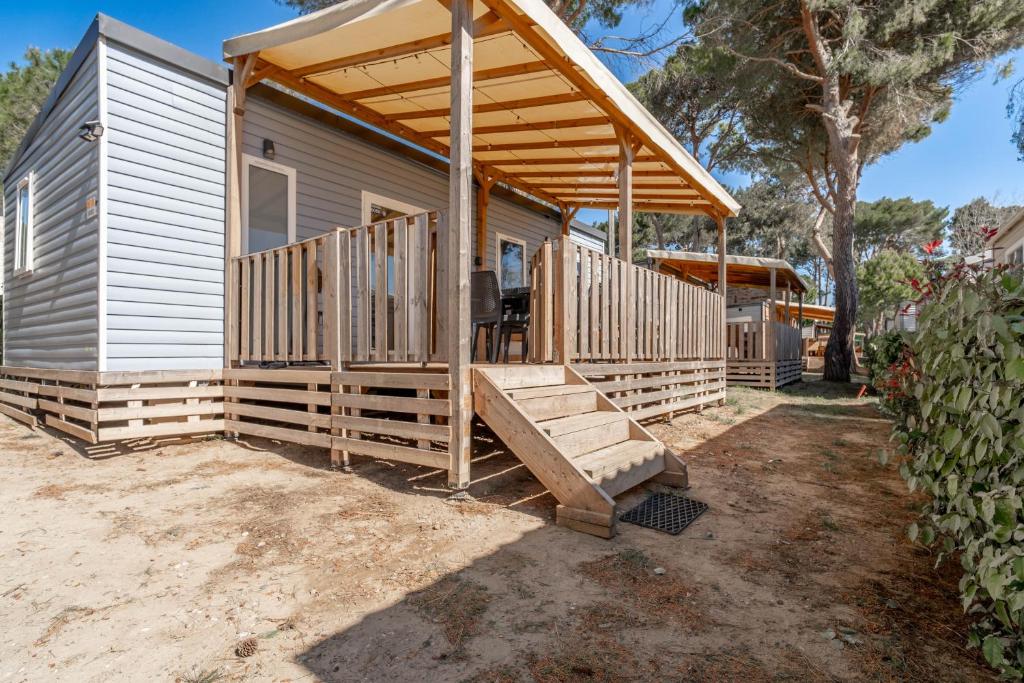 a small house with a porch and a deck at Mh sympa au camping domaine la yole in Vendres