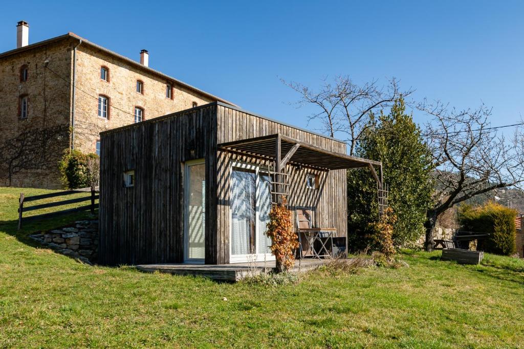 a small black house on a grassy field at Cabane Ecolodge La Chastanha in Saint-Symphorien-de-Mahun