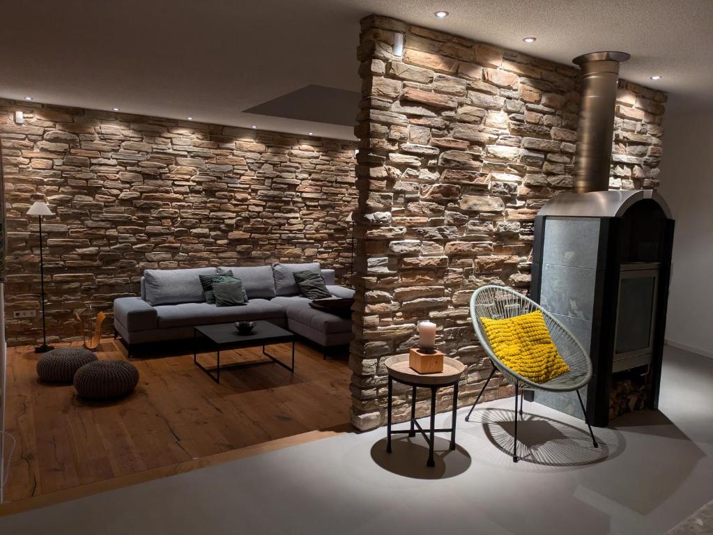a living room with a couch and a stone wall at Hygge Home Schwarzwald in Villingen-Schwenningen
