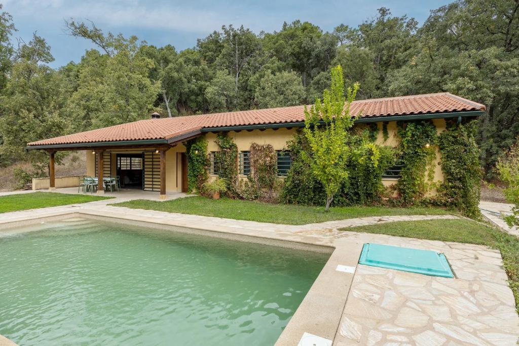 a home with a pool in front of a house at La Morada De Piedralaves in Piedralaves