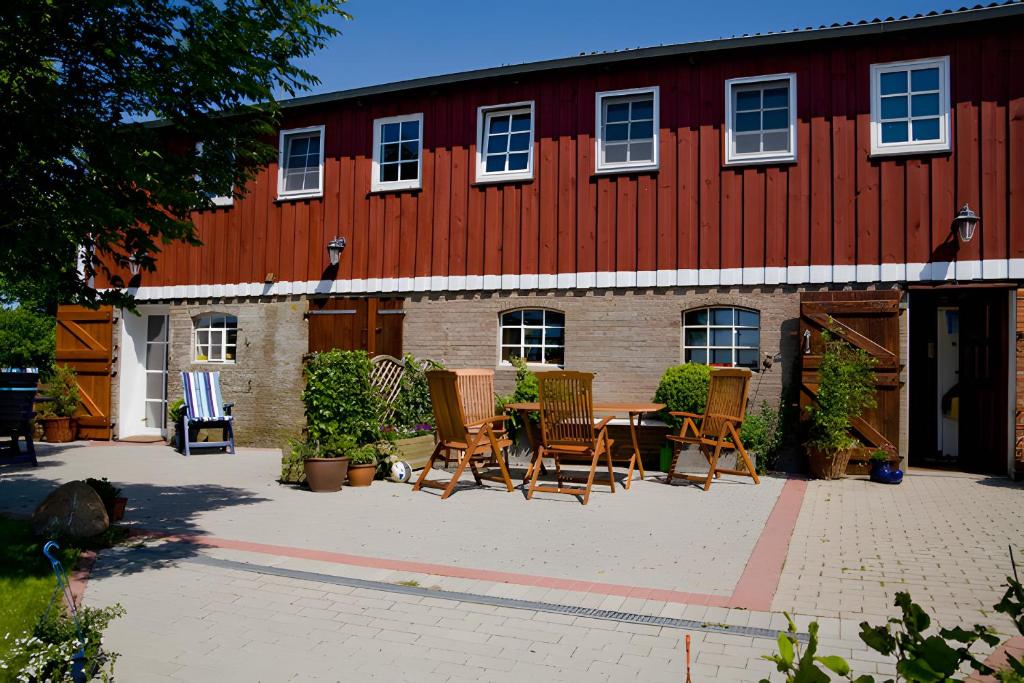 a patio with chairs and a table in front of a red barn at Ferienwohnungen Appelhof in Pellworm