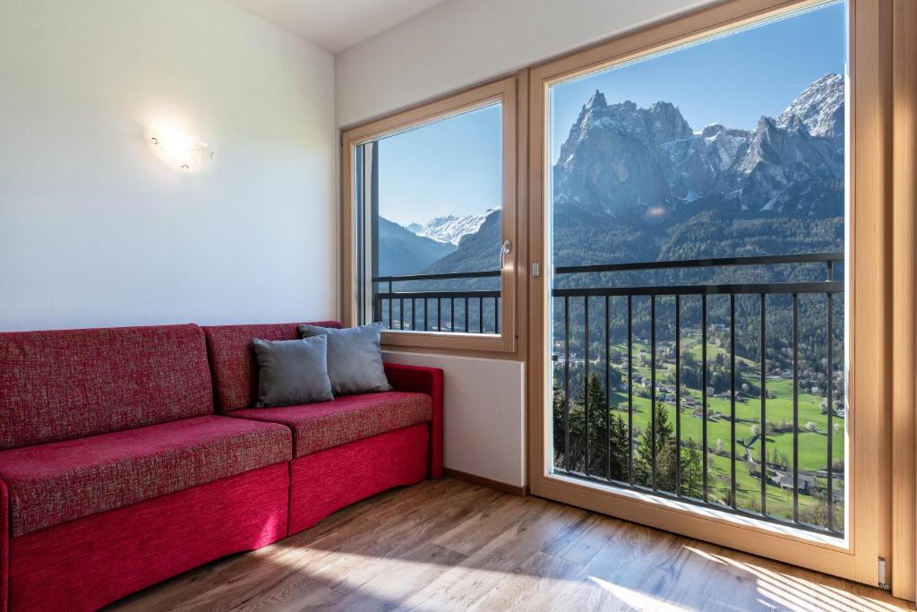 a living room with a red couch and a large window at Thusnelda Apartment A in Siusi
