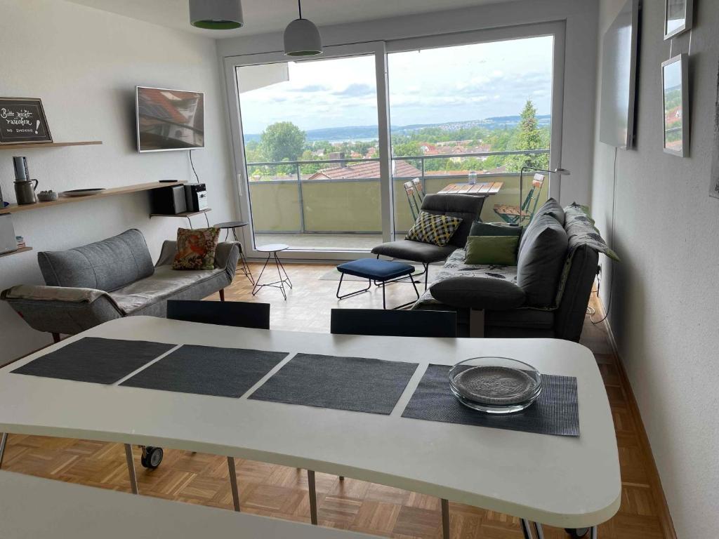 a living room with a table and chairs and a large window at Guck zum Bodensee in Uhldingen-Mühlhofen