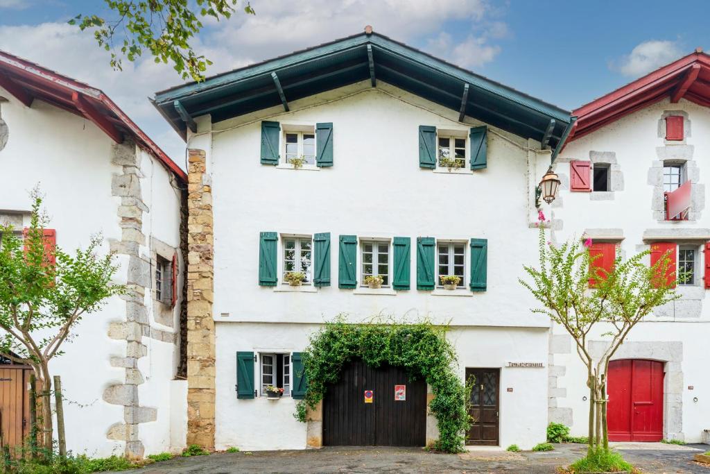 a white house with green shutters and a red door at Studio Tamburine Xaharra in Ainhoa