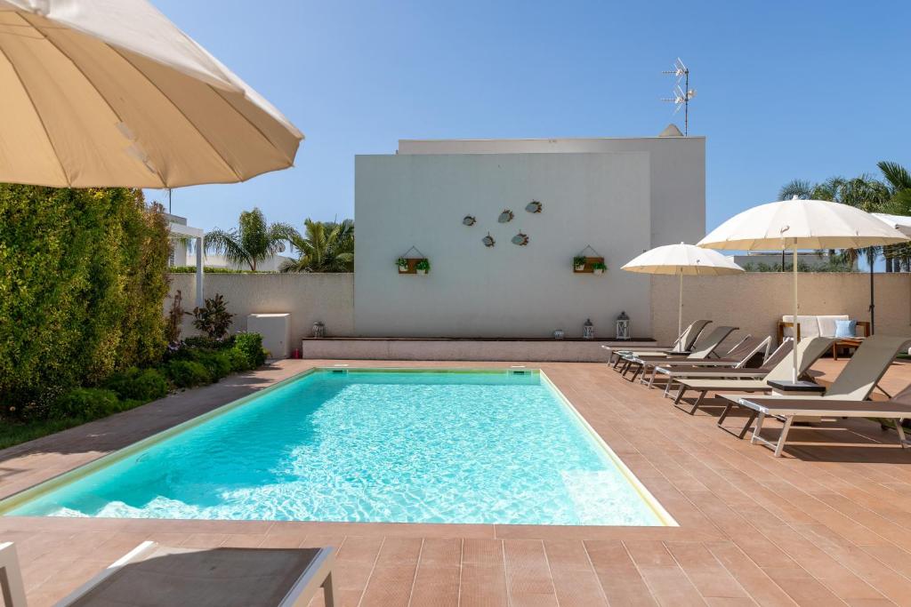a swimming pool with lounge chairs and umbrellas at Villa Heraia con piscina in Marina di Ragusa