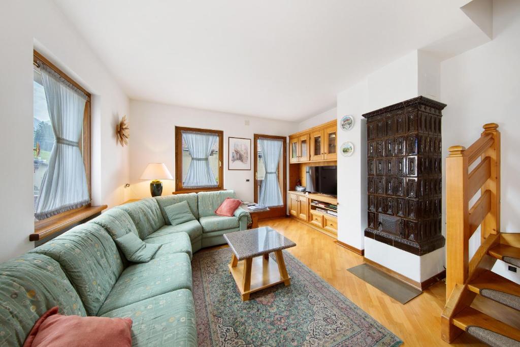 a living room with a green couch and a fireplace at Appartamento Al Pelmo a Vinigo in Vinigo