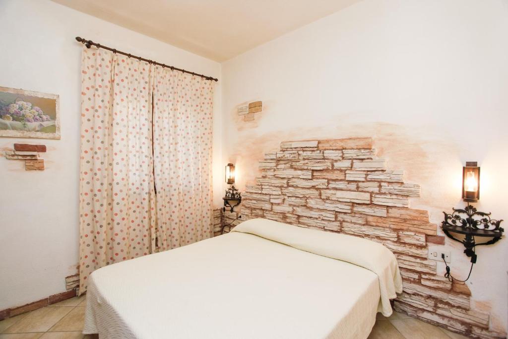 a bedroom with a white bed and a stone wall at mirtagru casa dell'olivastro in Agrustos