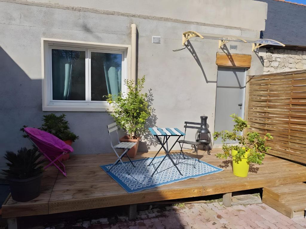 a patio with a table and chairs on a wooden deck at Chambre Écureuil in L'Ile-Bouchard