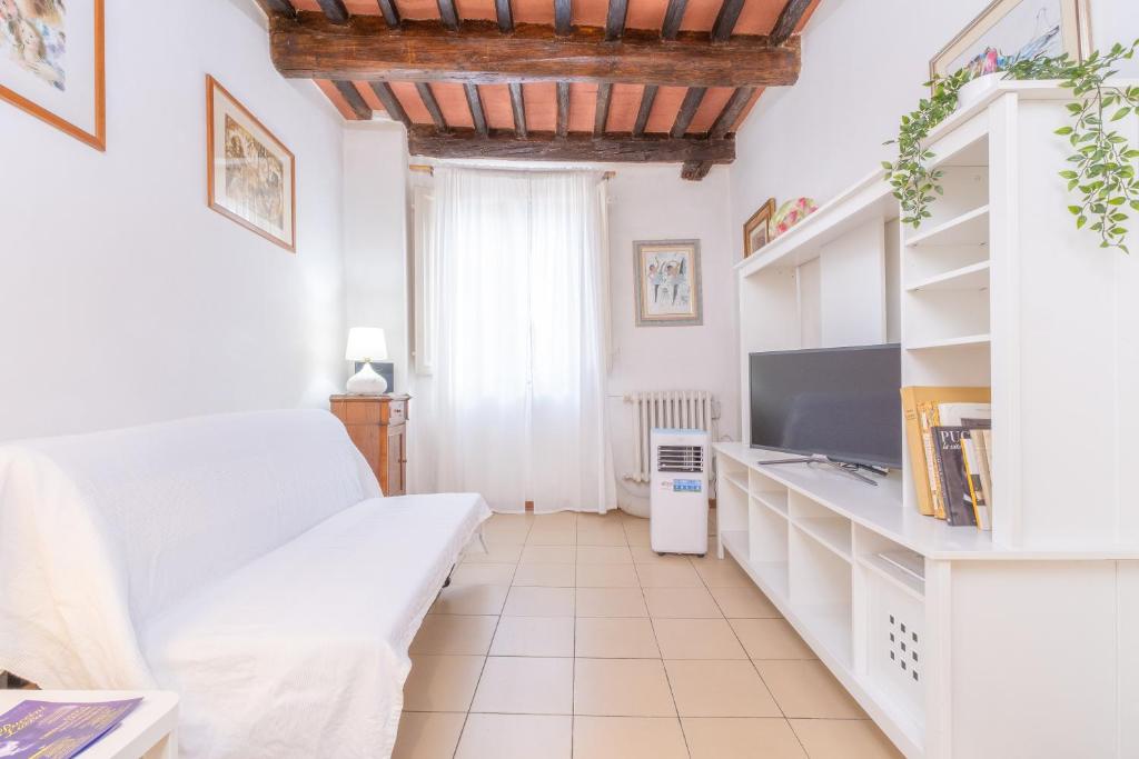 a white room with a bed and a tv at Il Nido - Immersi Nell'arte in Lucca