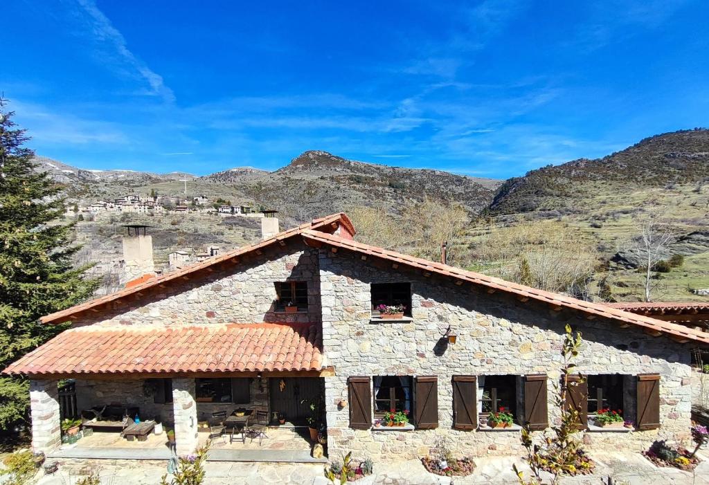 a stone house with mountains in the background at Casa Rural el Bac in Castellar de NʼHug