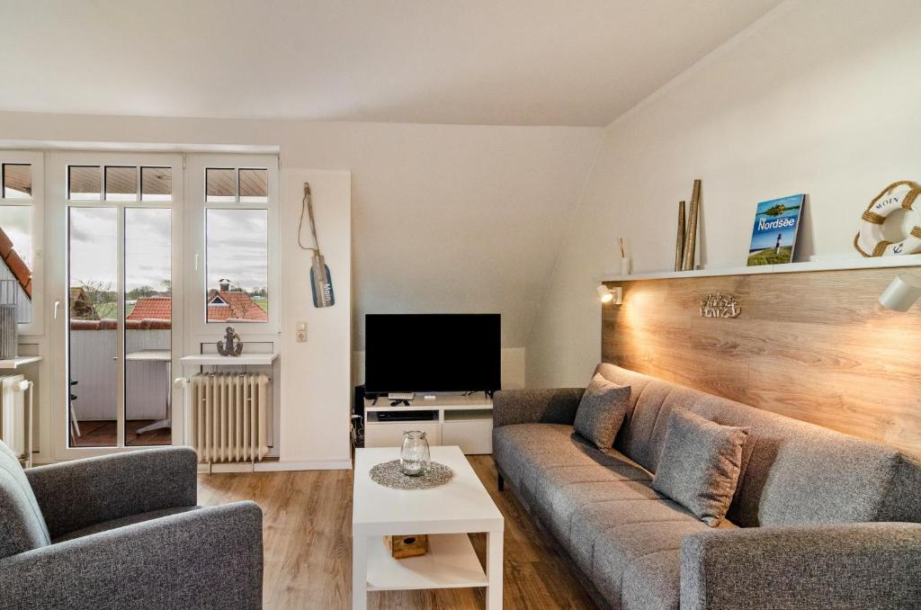 a living room with a couch and a tv at Ferienwohnung Boje 20 in Schillig