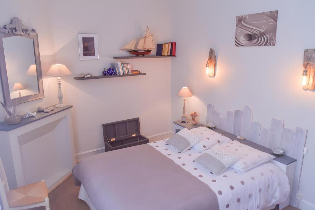 a white bedroom with a bed and a mirror at Gîte De La Voûte in Fécamp