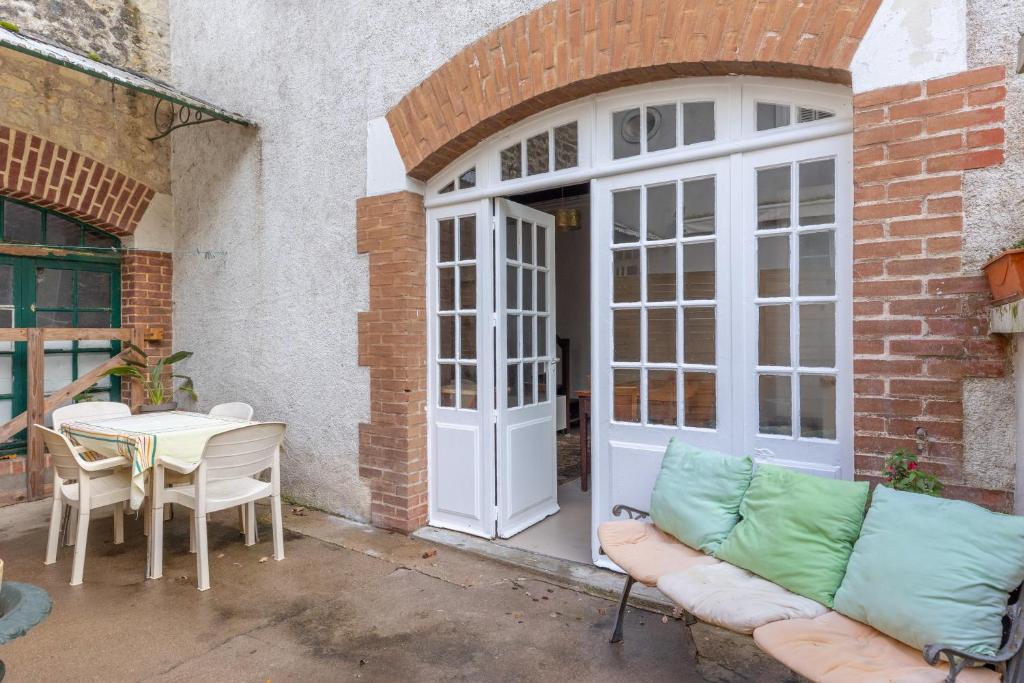 a patio with a white door and a table and chairs at La maison blanche in Nazelles