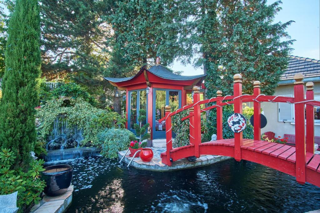 a red bridge over a pond in a garden at Au printemps Japonais in Pierre-Châtel