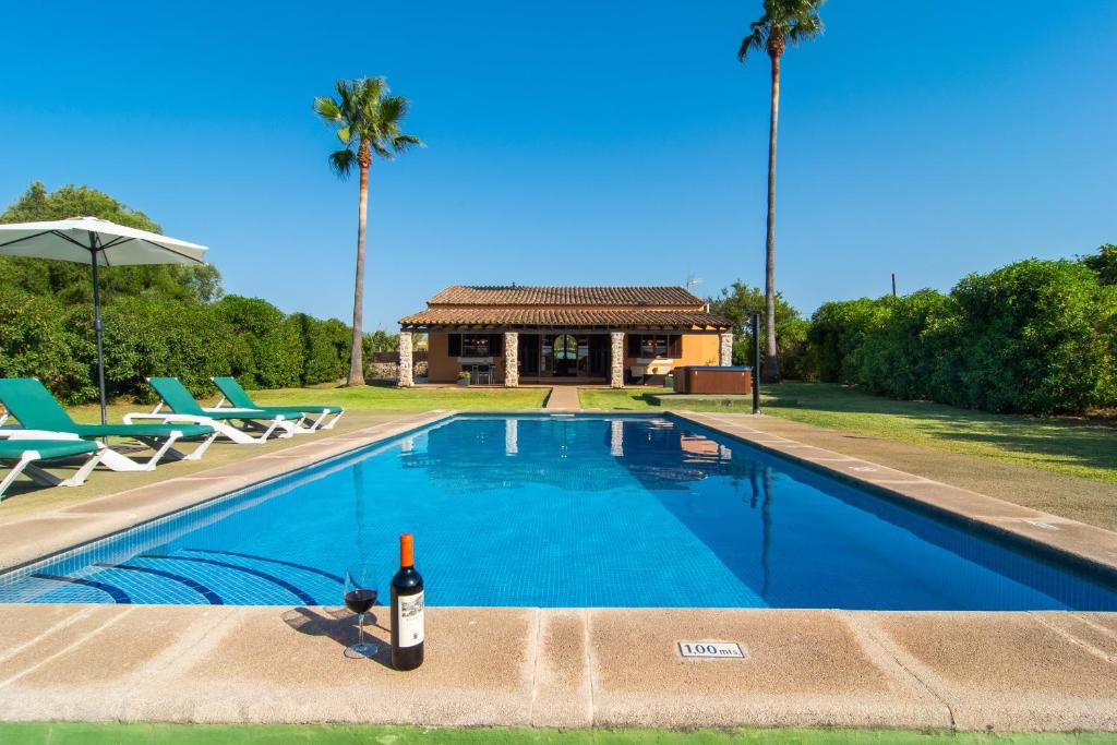 a bottle of wine sitting on a ledge next to a swimming pool at Finca Pollentia in Alcudia
