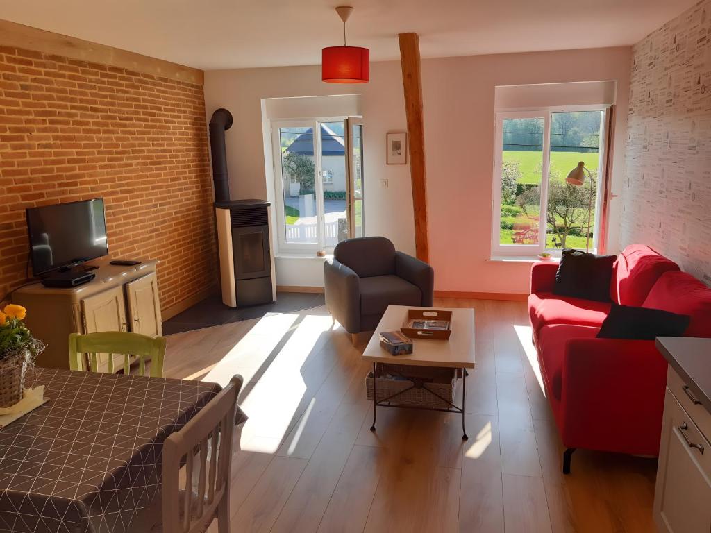 a living room with a red couch and a tv at La Grange Aux Oiseaux in Beaulieu