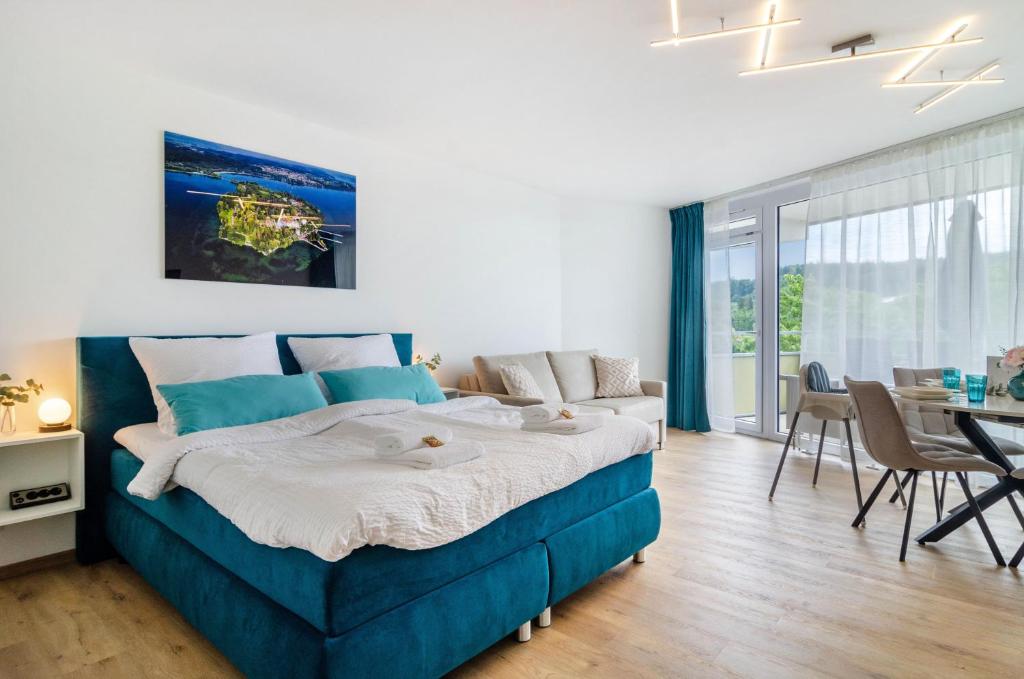 a bedroom with a blue bed and a table and chairs at Ferienwohnung Mainaublick in Uhldingen-Mühlhofen