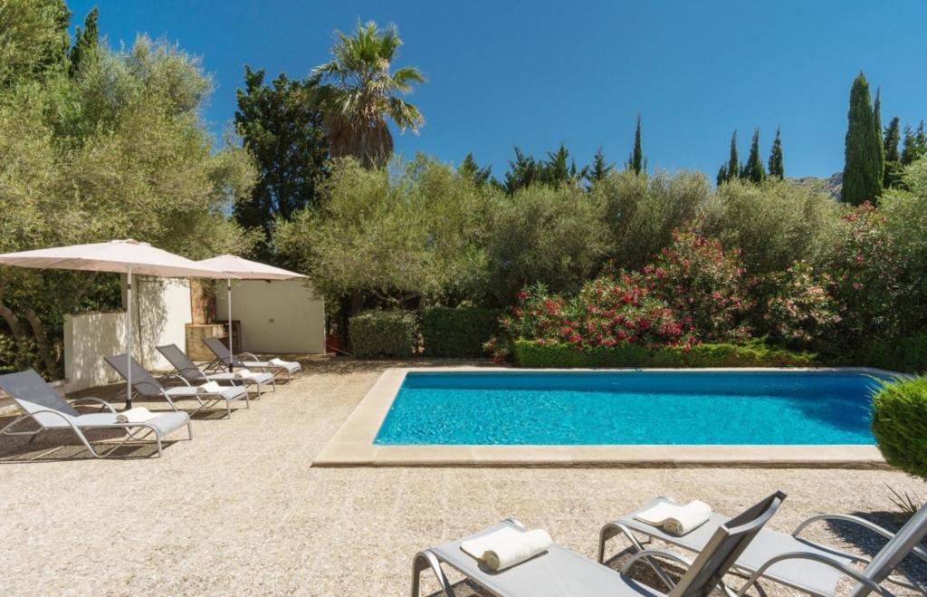 a swimming pool with lounge chairs and an umbrella at Llangana in Pollença