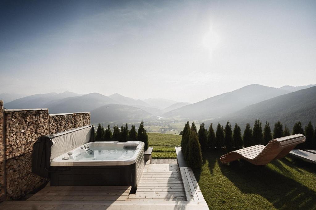 a bath tub on a patio with a view of mountains at Rueper Hof Chalet Dolomit in Valdaora
