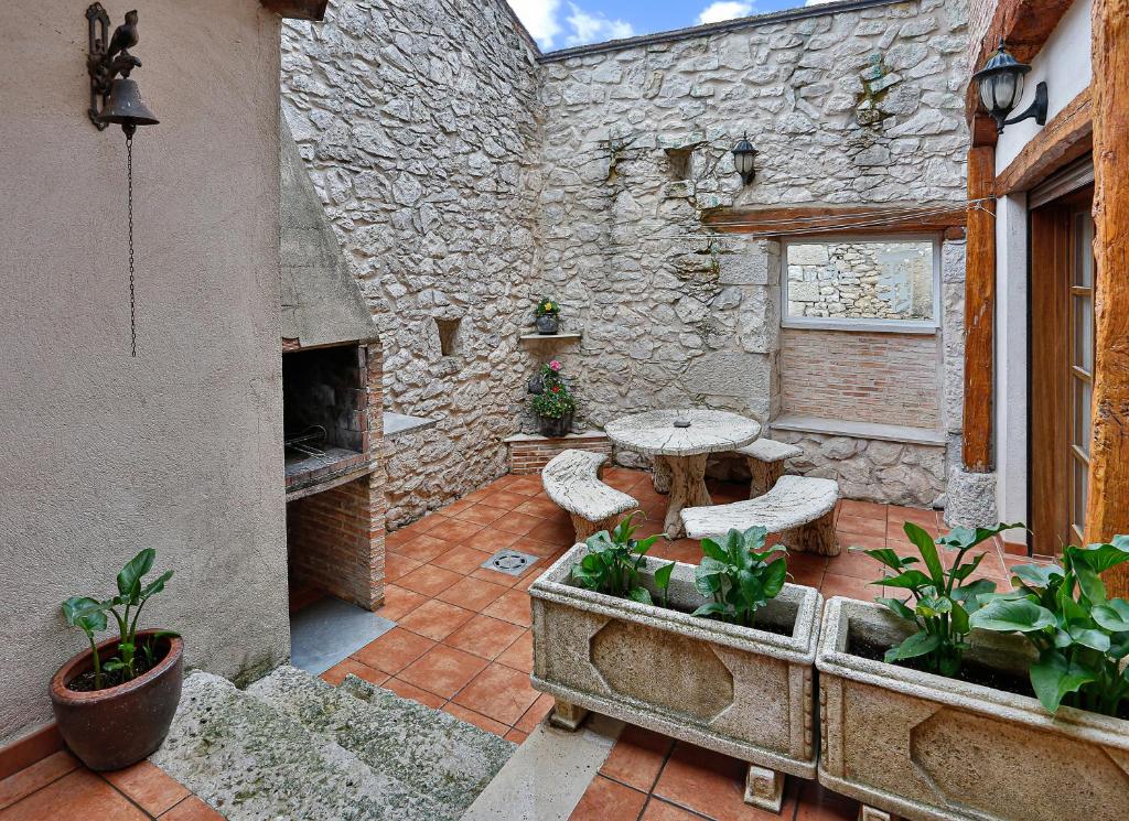 an outdoor patio with a table and a stone wall at El Lagar in Canalejas de Peñafiel