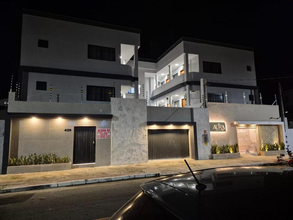 a large white building with a car parked in front of it at Praia Do Morro Suites Para Grupos Guarapari-es in Guarapari