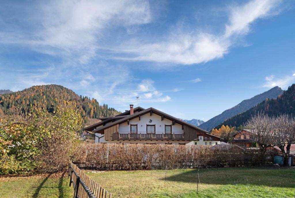 a house in a field next to a fence at Residence Malibu Appartamento 8 in Falcade