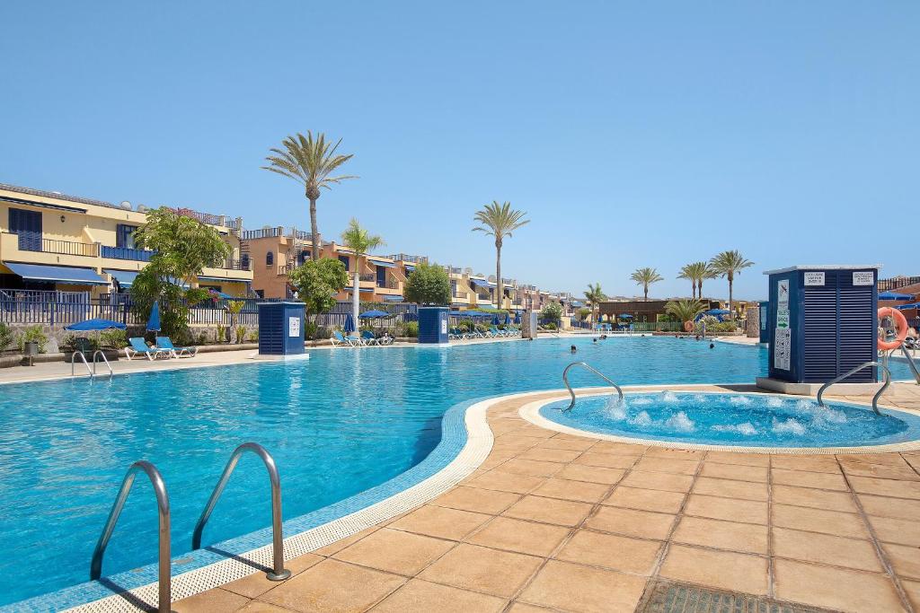 a large swimming pool in a resort with palm trees at Free Airport Shuttle and Parking in San Bartolomé