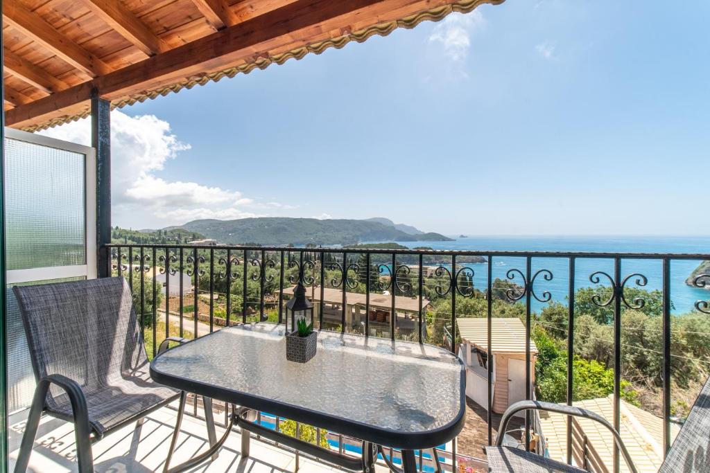 a table and chairs on a balcony with the ocean at Spyridoula Studio 12 in Paleokastritsa
