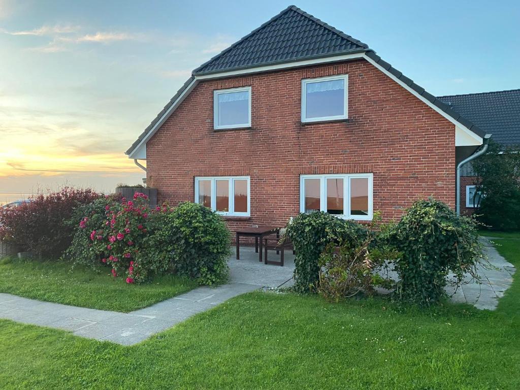 a brick house with a picnic table in the yard at Gaestehaus Nuke in Langeneß