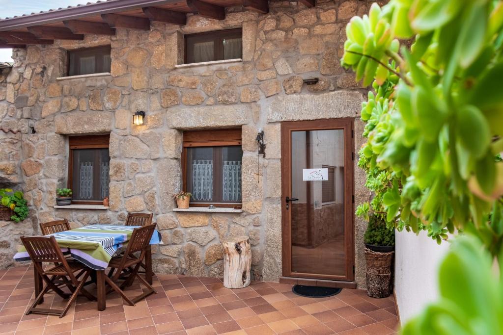 a stone house with a table and a dog in front of it at Casa La Charca in Amavida