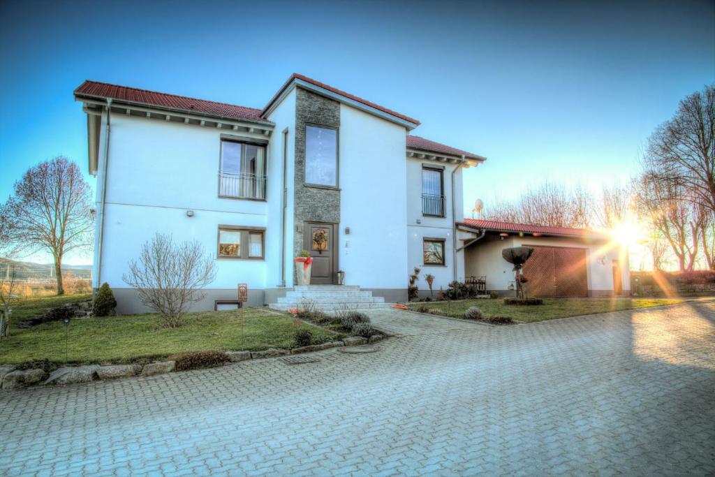 a white house with a stone driveway at Ferienwohnung Lindenhof in Dormettingen