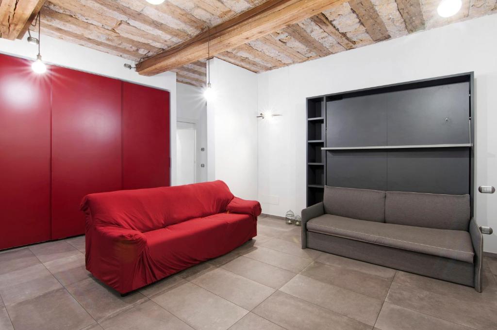 a living room with a red couch and a tv at La Sartoria in Porlezza