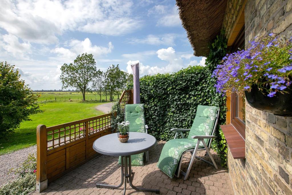 a patio with a table and chairs and a fence at Ferienwohnung am Eiderdeich in Delve