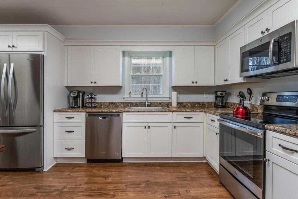 a kitchen with white cabinets and stainless steel appliances at Bike Path Getaway in Town · On bike path, NEW KITCHEN,walk to St in Brevard
